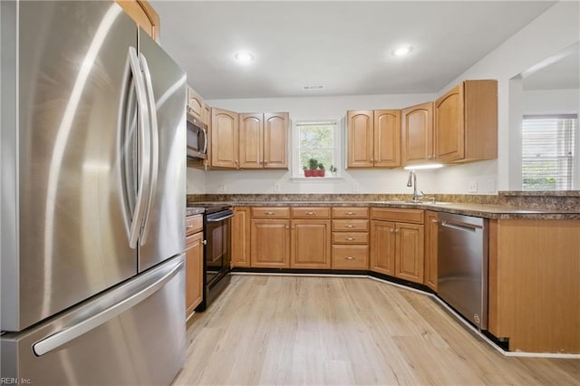 kitchen with visible vents, dark countertops, light wood-type flooring, a sink, and appliances with stainless steel finishes