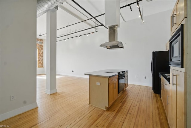 kitchen with rail lighting, island exhaust hood, black appliances, and light wood-style floors