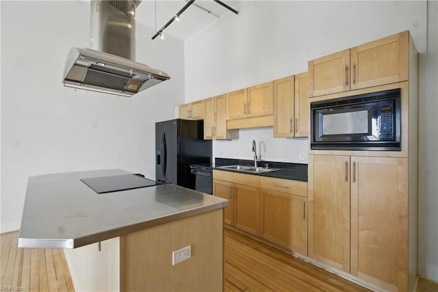 kitchen featuring island range hood, rail lighting, a sink, black appliances, and light wood-style flooring