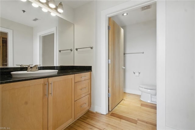 bathroom featuring visible vents, vanity, baseboards, toilet, and hardwood / wood-style floors