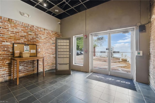 doorway with a high ceiling, tile patterned flooring, and brick wall