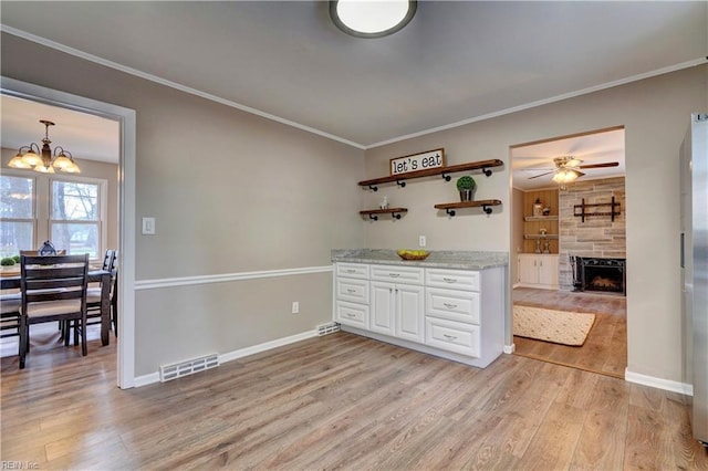 kitchen featuring visible vents, open shelves, white cabinetry, a large fireplace, and light wood finished floors