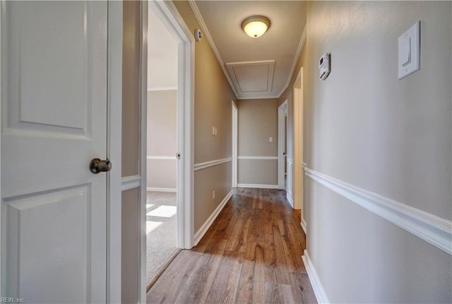 hall featuring baseboards, wood finished floors, and attic access
