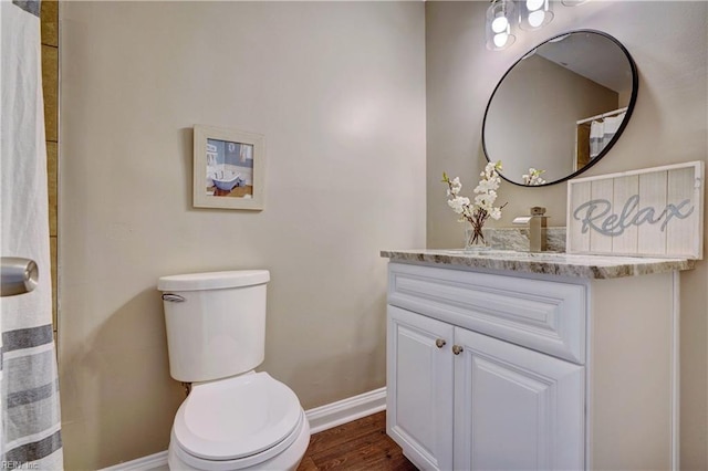 full bathroom featuring toilet, baseboards, wood finished floors, and vanity