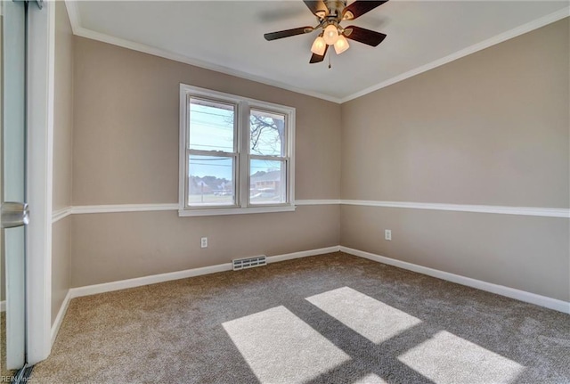 carpeted empty room featuring crown molding, baseboards, ceiling fan, and visible vents