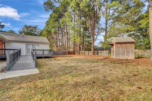 view of yard featuring a deck, an outbuilding, a fenced backyard, and a storage unit