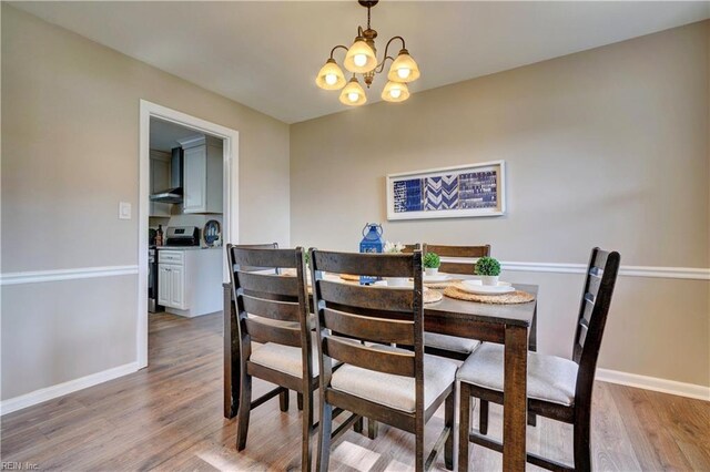 dining space with baseboards, a chandelier, and wood finished floors