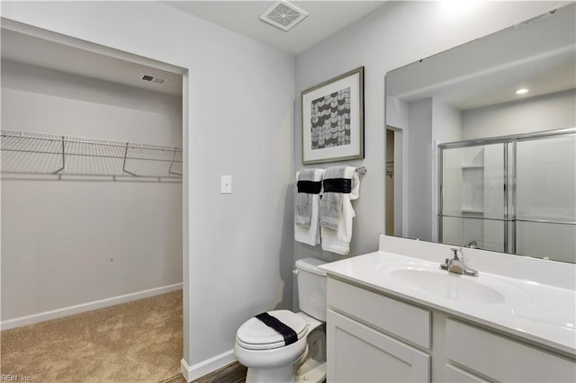 bathroom with vanity, toilet, baseboards, a shower stall, and visible vents