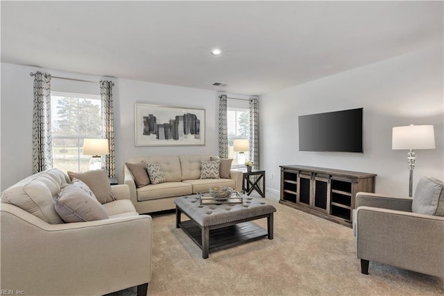 living area with a healthy amount of sunlight, light carpet, recessed lighting, and visible vents