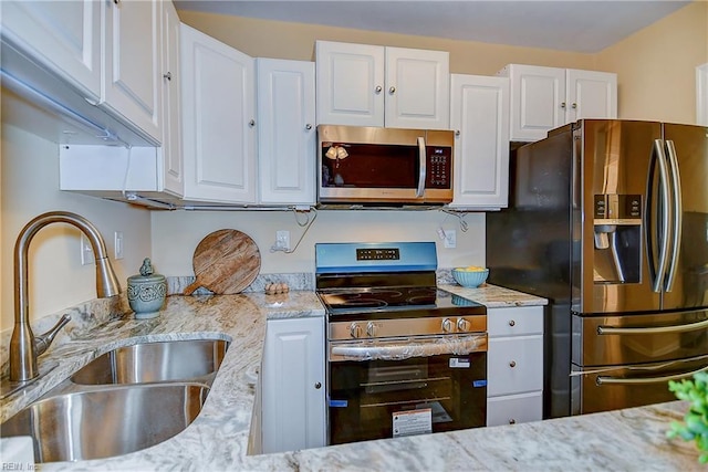 kitchen with white cabinetry, appliances with stainless steel finishes, a sink, and light stone counters