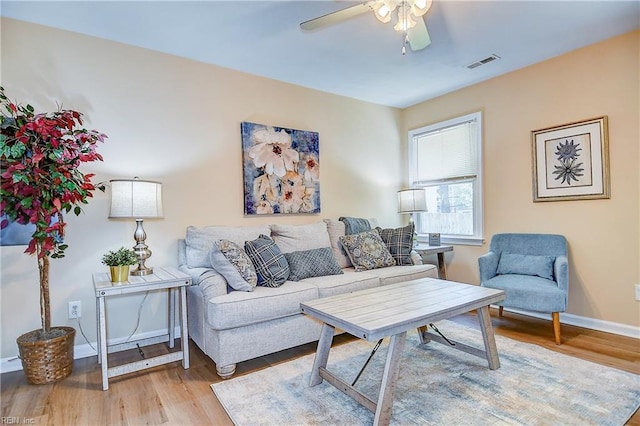 living room featuring visible vents, a ceiling fan, baseboards, and wood finished floors