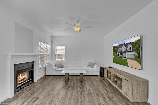 157 Pier Lndg, South Mills, NC 27976 - living room with a warm lit fireplace, a textured ceiling, a ceiling fan, baseboards, and wood finished floors