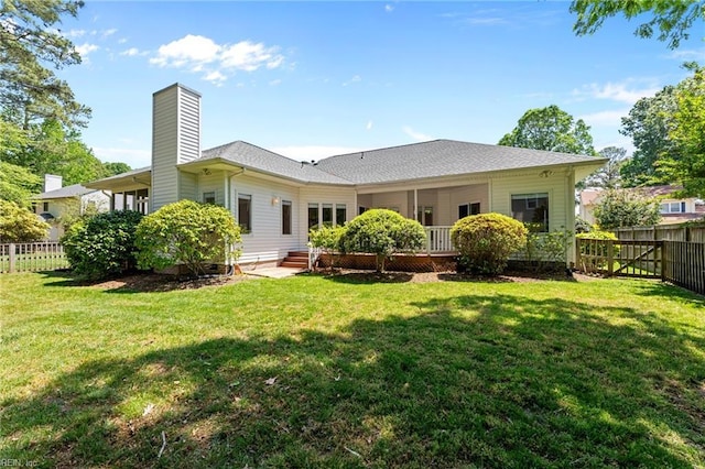 rear view of property featuring fence, a yard, and a chimney