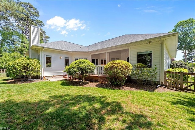 back of property with fence, a wooden deck, a chimney, and a yard
