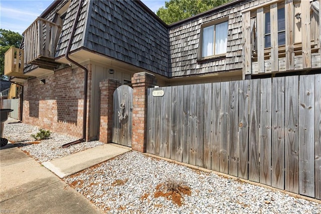 1132 Ocean Pebbles Way, Virginia Beach, VA 23451 - view of exterior entry with fence, a balcony, mansard roof, brick siding, and a gate