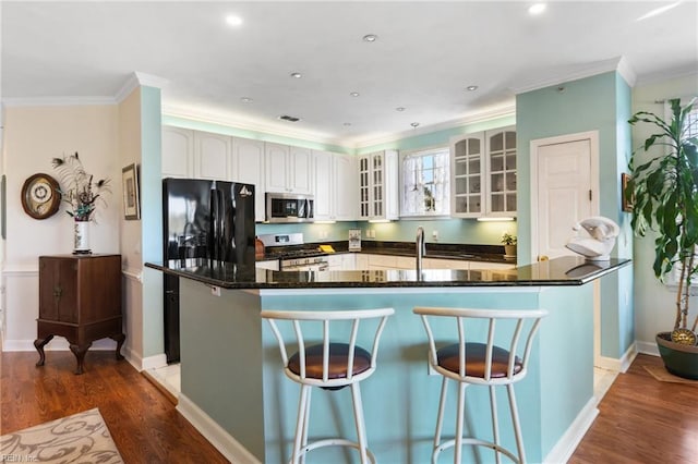 kitchen with stainless steel appliances, glass insert cabinets, wood finished floors, and a kitchen bar