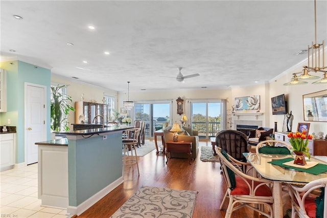 dining space featuring crown molding, ceiling fan, a fireplace, and recessed lighting