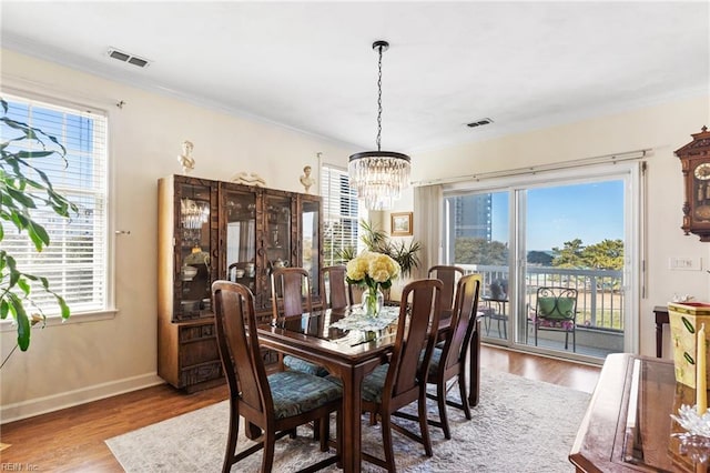 dining area with an inviting chandelier, wood finished floors, and visible vents
