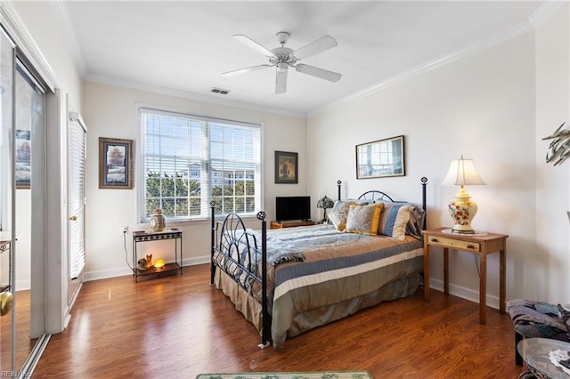 bedroom featuring crown molding, baseboards, visible vents, and wood finished floors