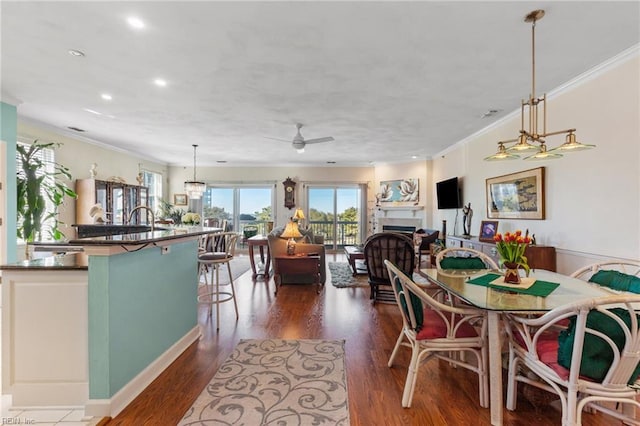dining area with crown molding, a fireplace, a ceiling fan, recessed lighting, and dark wood-type flooring