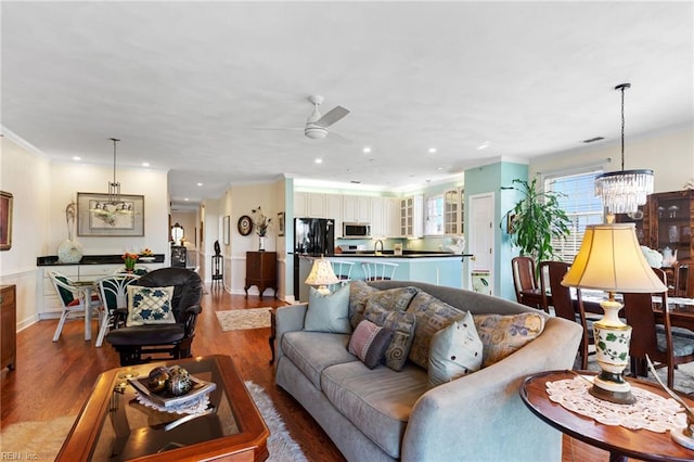living area featuring recessed lighting, ornamental molding, wood finished floors, and ceiling fan with notable chandelier
