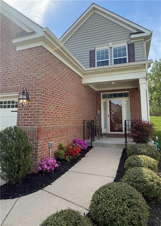 entrance to property featuring a porch and brick siding