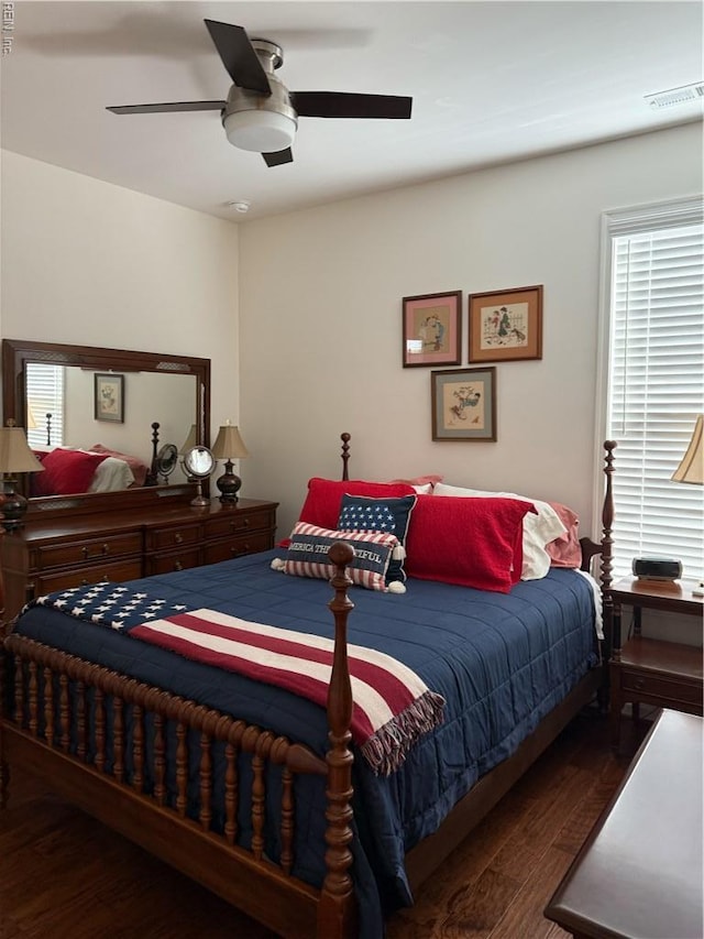 bedroom with visible vents, a ceiling fan, wood finished floors, and multiple windows