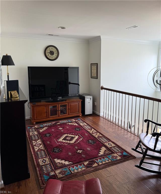 living area with baseboards, ornamental molding, and wood finished floors