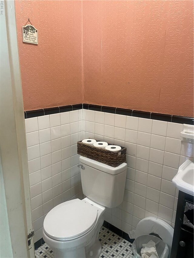 bathroom featuring tile walls, a textured wall, and toilet
