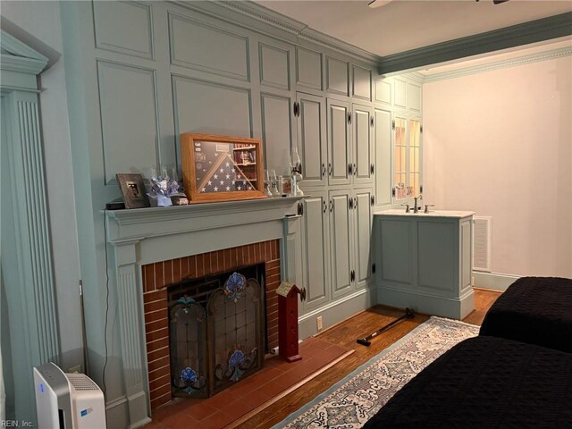 living area featuring light wood-style floors, ornamental molding, a fireplace, and visible vents