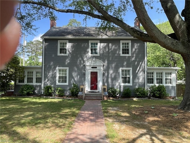 colonial-style house with a chimney and a front yard
