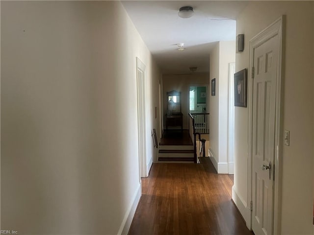 corridor featuring baseboards and dark wood-style flooring