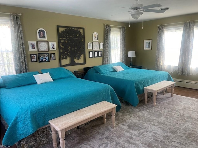 bedroom with a ceiling fan, visible vents, and baseboard heating