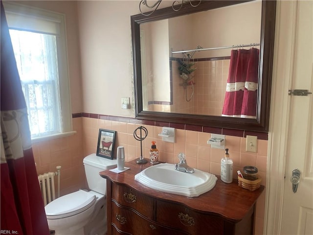 bathroom with tile walls, a wainscoted wall, vanity, toilet, and radiator heating unit