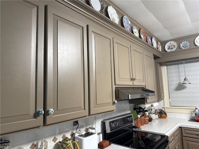 kitchen featuring electric range oven, tile counters, under cabinet range hood, backsplash, and gray cabinetry