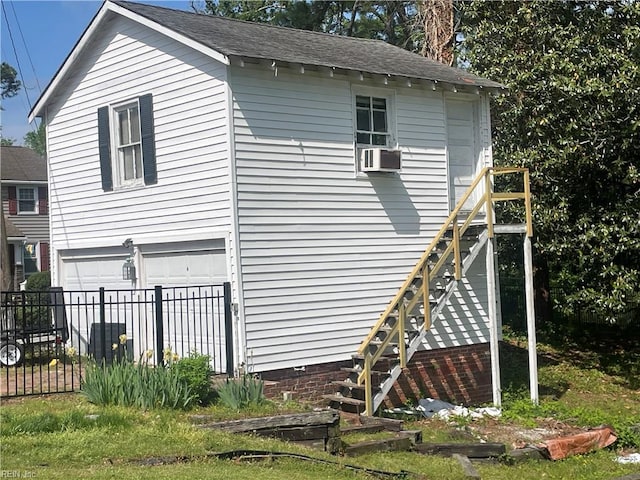 view of side of property with fence, stairs, a shingled roof, and a garage