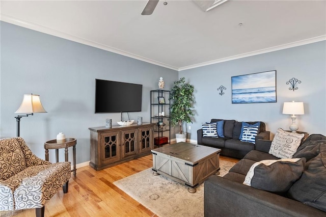 living room featuring a ceiling fan, baseboards, ornamental molding, and light wood-style flooring