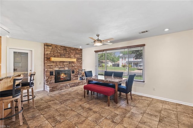 dining space with a ceiling fan, baseboards, visible vents, and a fireplace