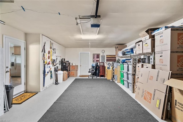garage with a garage door opener, electric panel, and stainless steel refrigerator with ice dispenser