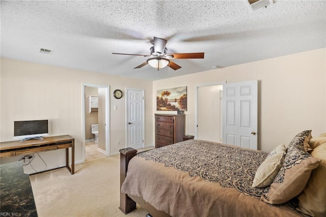 bedroom featuring visible vents, light carpet, ceiling fan, a textured ceiling, and ensuite bath