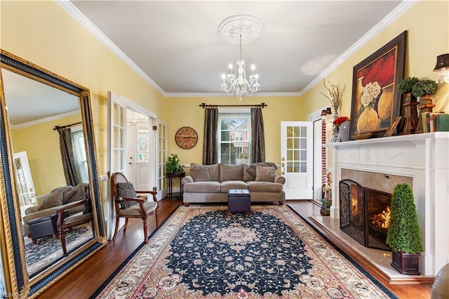 living room featuring crown molding, wood finished floors, a premium fireplace, and an inviting chandelier
