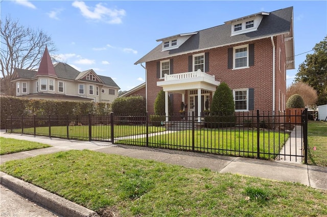 view of front facade with a shingled roof, a fenced front yard, a front lawn, and brick siding