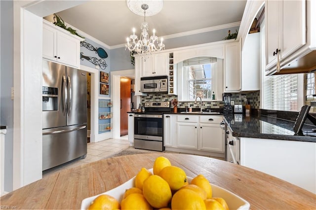 kitchen with crown molding, white cabinetry, backsplash, and stainless steel appliances