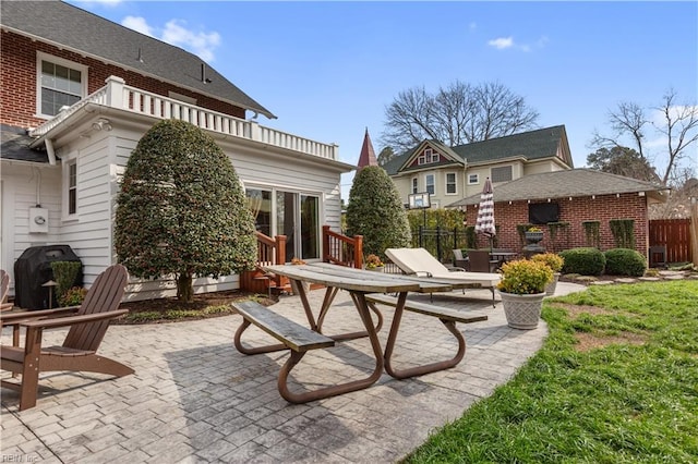 rear view of house with brick siding, a patio, and fence