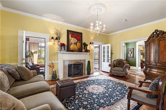 living room with a fireplace, wood finished floors, baseboards, a chandelier, and ornamental molding