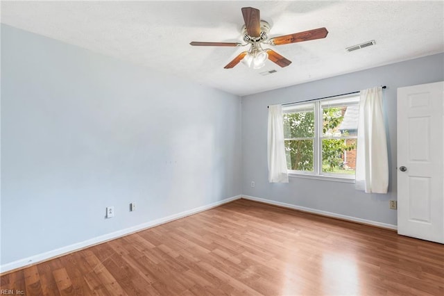 unfurnished room featuring ceiling fan, baseboards, visible vents, and wood finished floors