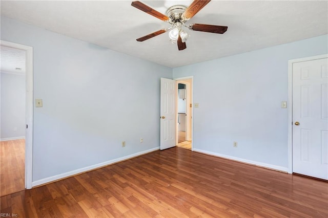 empty room featuring ceiling fan, baseboards, and wood finished floors