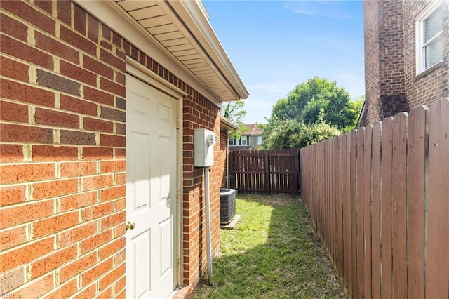 view of side of property with brick siding, fence, and central AC unit