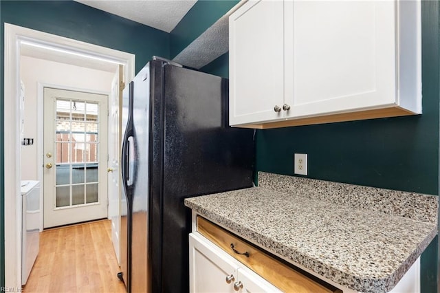 kitchen featuring freestanding refrigerator, light wood finished floors, white cabinets, and washer / clothes dryer