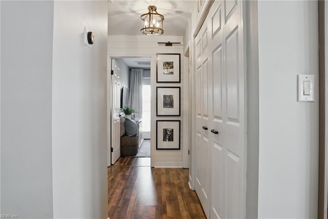 hallway with dark wood-style floors and a chandelier